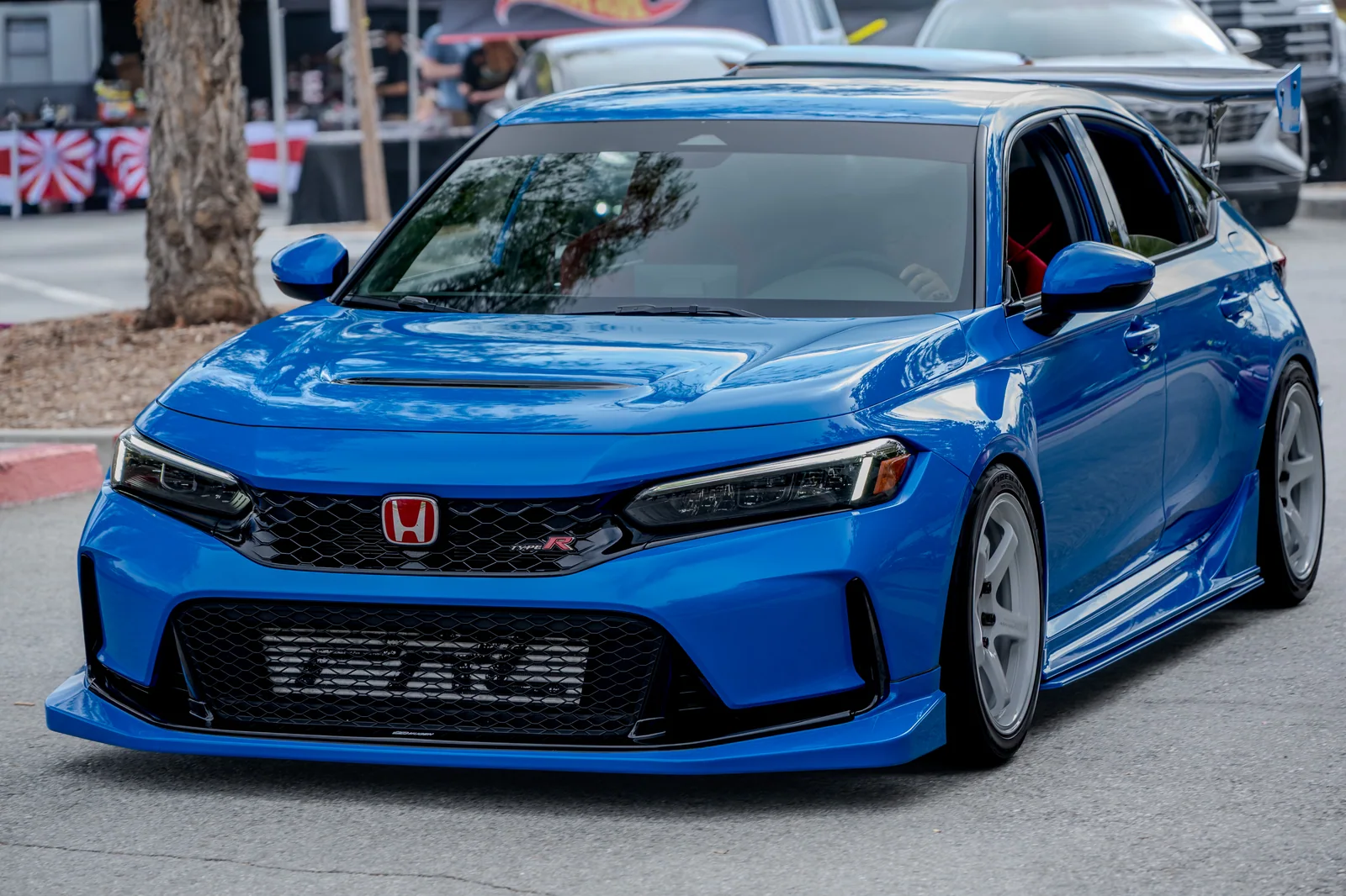Blue Honda Civic Type R seen from the front three-quarter angle, with white wheels and a large rear wing.