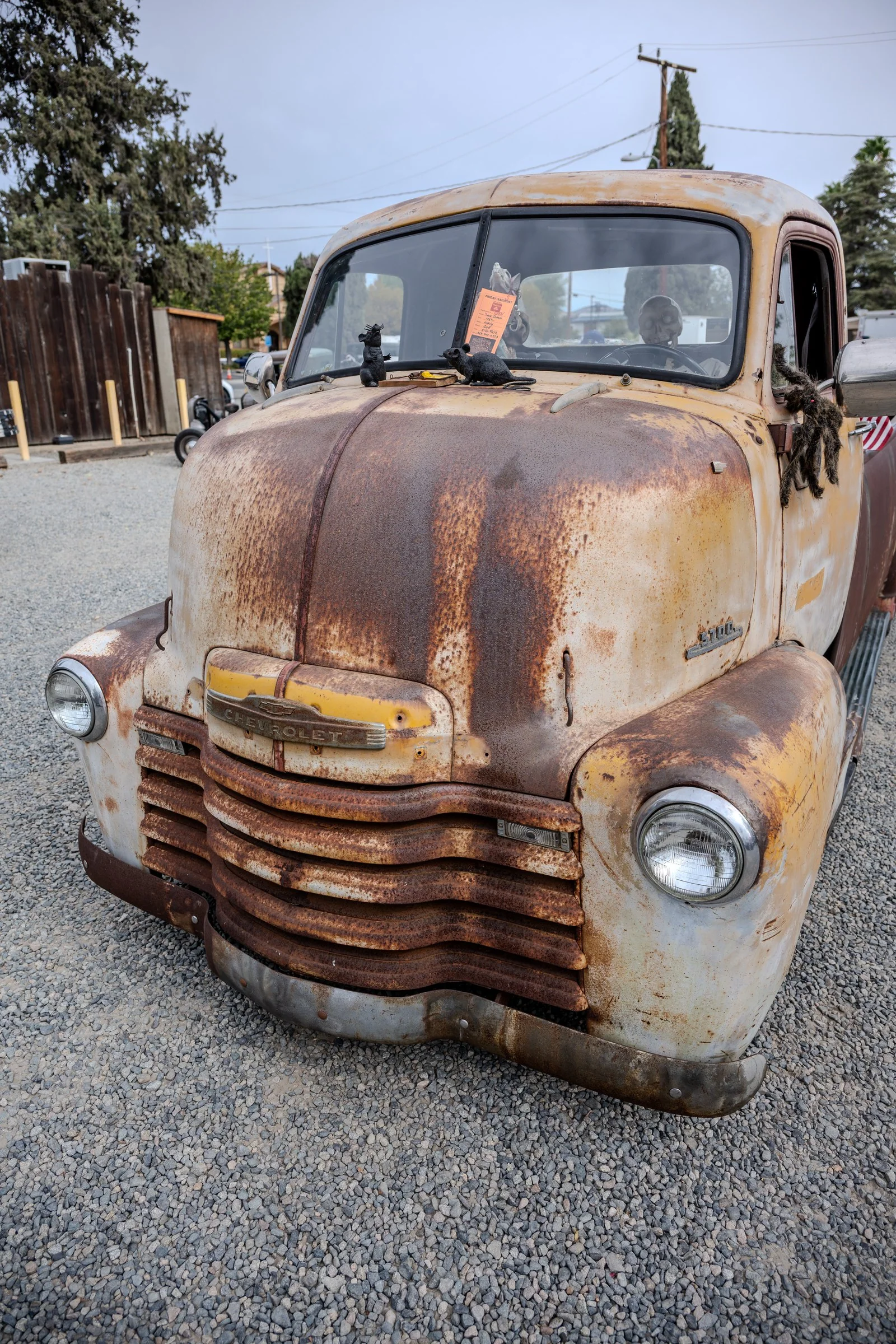 Weathered vintage pickup cab with faded yellow paint and rust-colored surfaces.