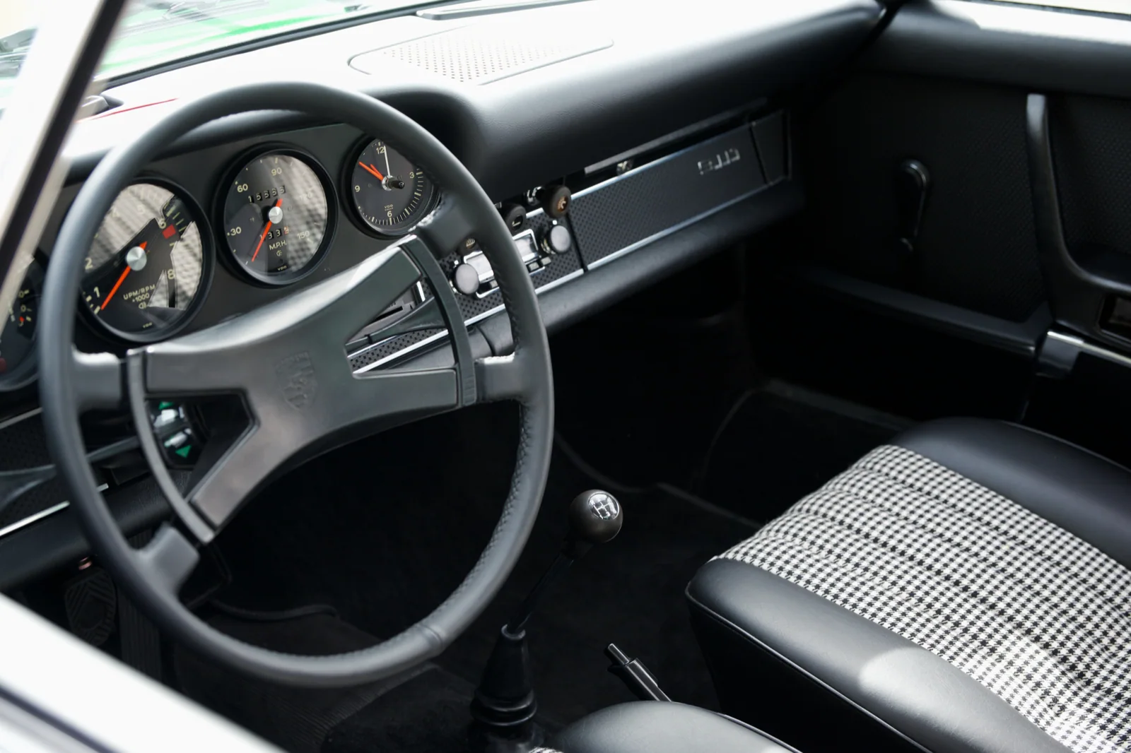 Porsche 911T cockpit with steering wheel, instruments, gear lever, and patterned seats.