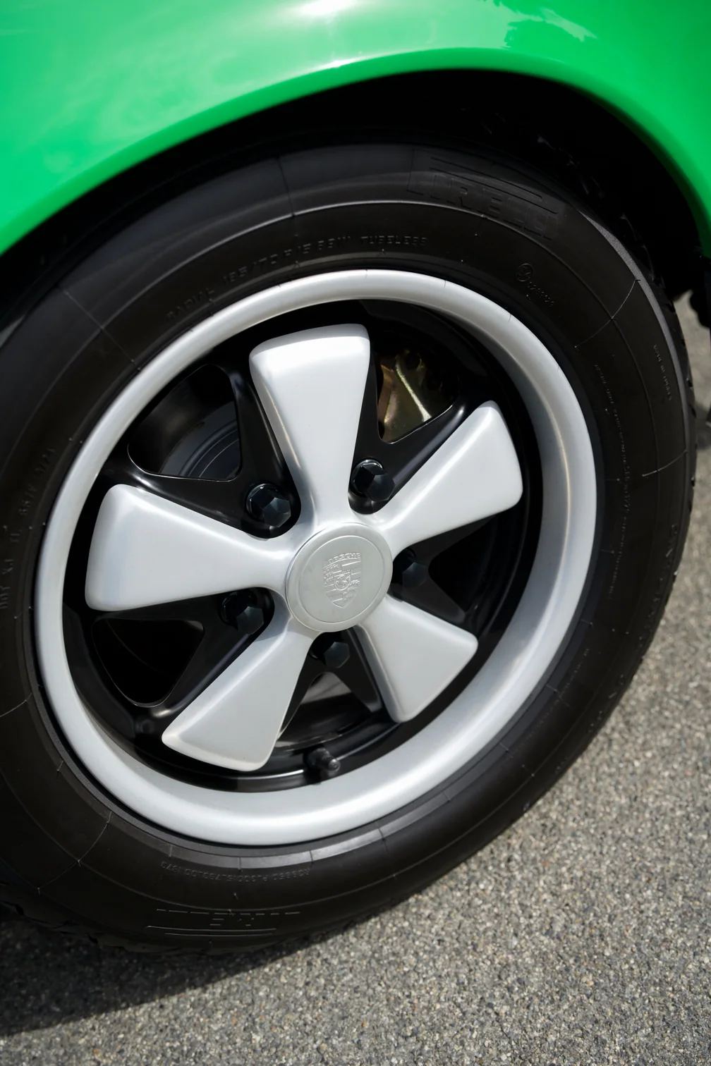Porsche wheel with silver spokes and a black tire.