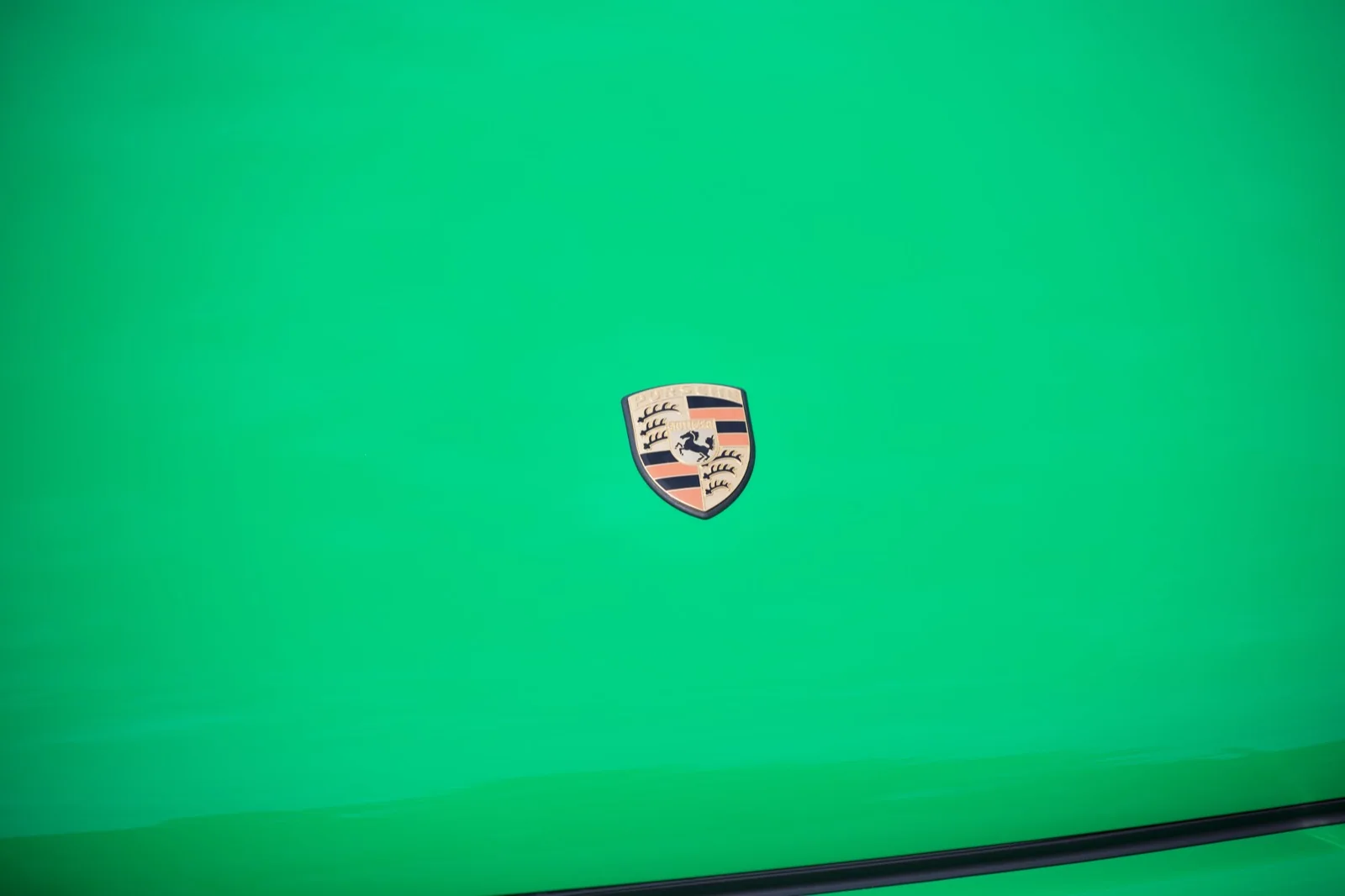 Porsche crest on green paint; an editorial detail study.