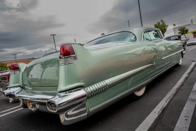 Long mint-green Cadillac photographed from the rear three-quarter angle.