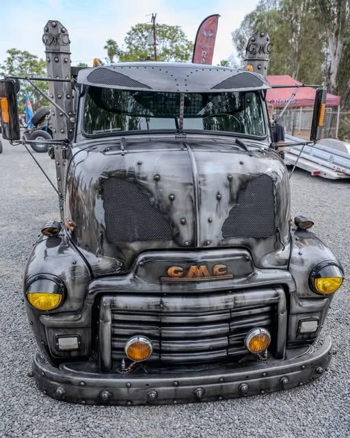 Weathered GMC truck at an outdoor car gathering.