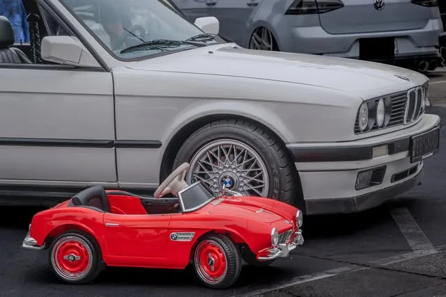 Red toy roadster in front of a silver BMW.